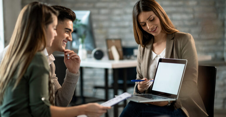 Happy couple and their insurance agent using laptop on a meeting in the office.