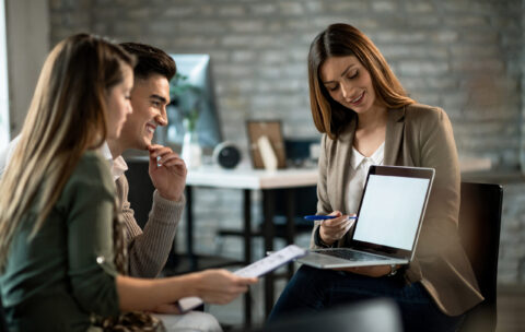 Happy couple and their insurance agent using laptop on a meeting in the office.