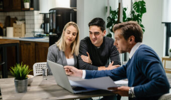 Smiling couple using a computer with their investment agent on a meeting.